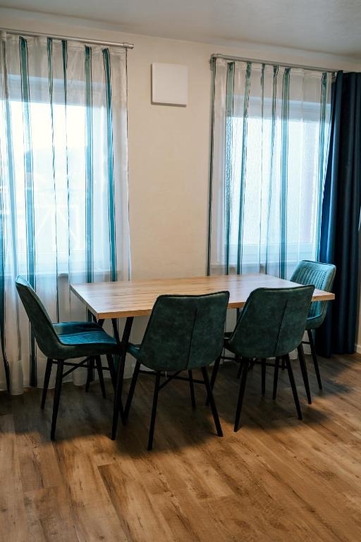 Esstisch mit vier Stühlen am Fenster in einem Apartment des dillhotel Ilsede