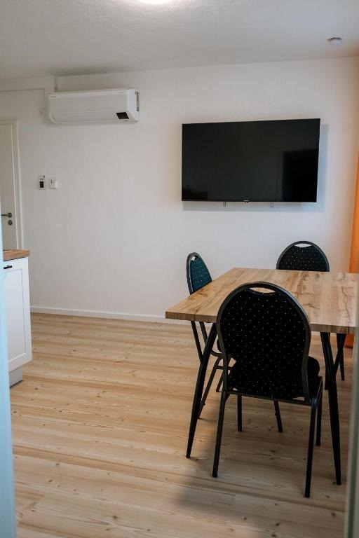 Wohnbereich mit Fernseher, Esstisch und Klimagerät in einem Apartment des dillhotel