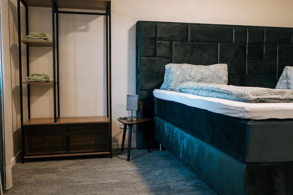 Schlafbereich mit Einzelbett, Nachttisch und offenem Regal in einem Apartment des dillhotel
