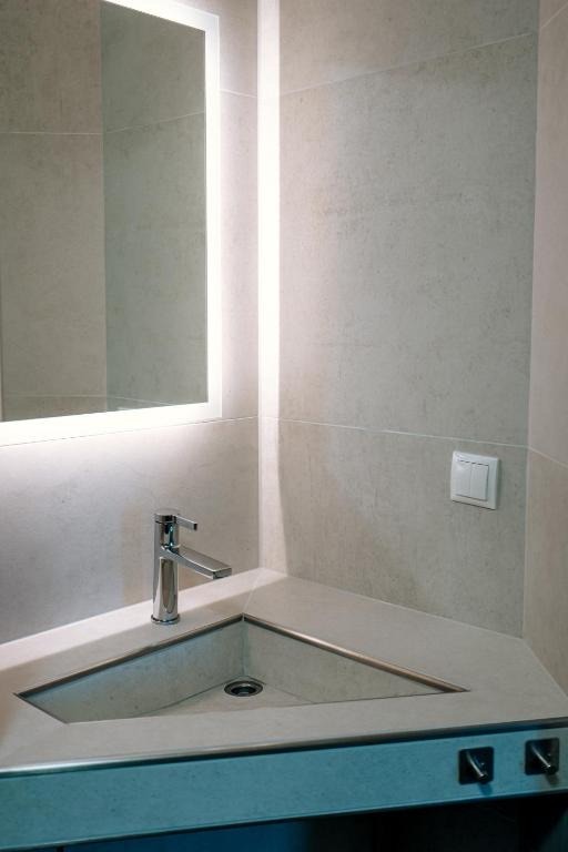 Waschbecken mit beleuchtetem Spiegel im Bad eines Apartments des dillhotel