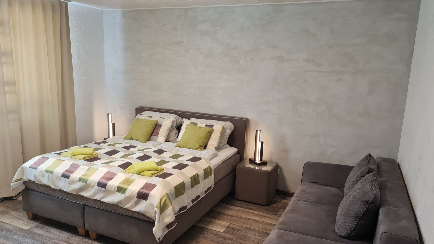 Schlafbereich eines Zimmers im dillhotel Ilsede mit breitem Bett und Sofa