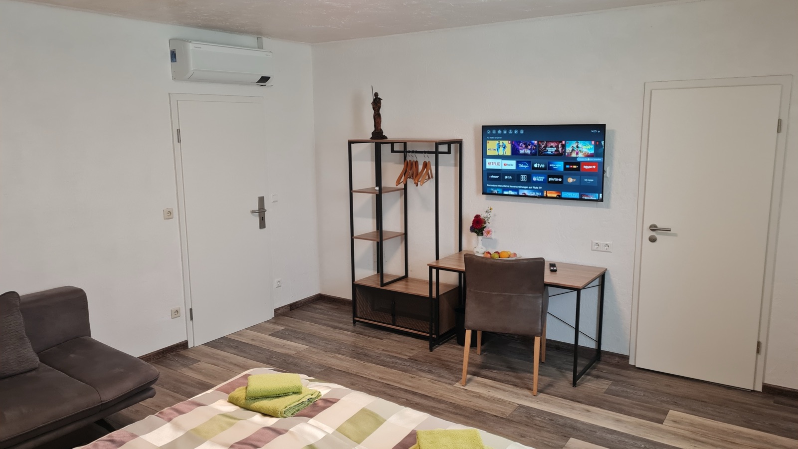 Wohnbereich mit Schreibtisch, Fernseher und Sitzgelegenheit in Zimmer 6