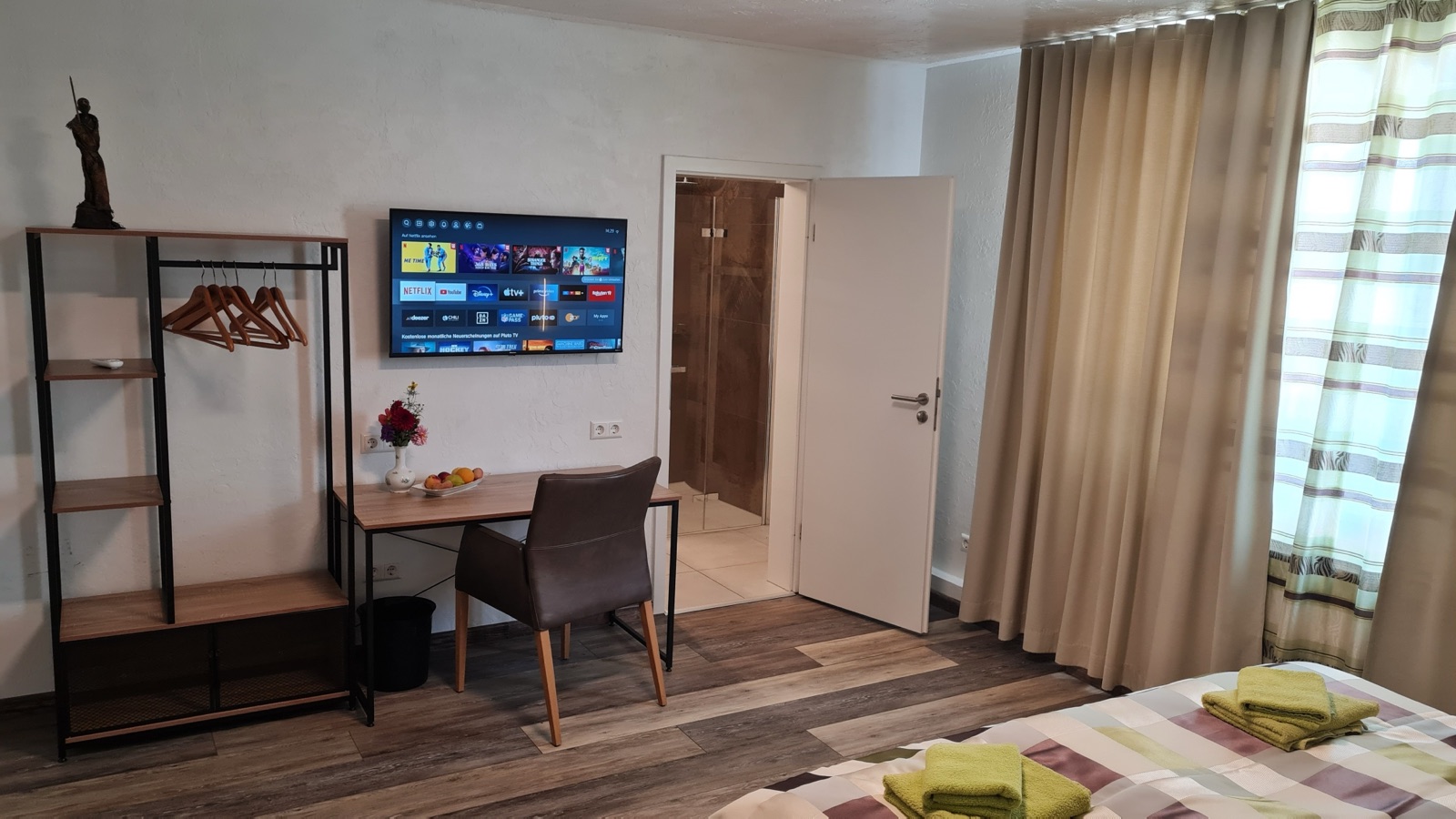 Wohnbereich mit Regal, Schreibtisch und Tür in Zimmer 6