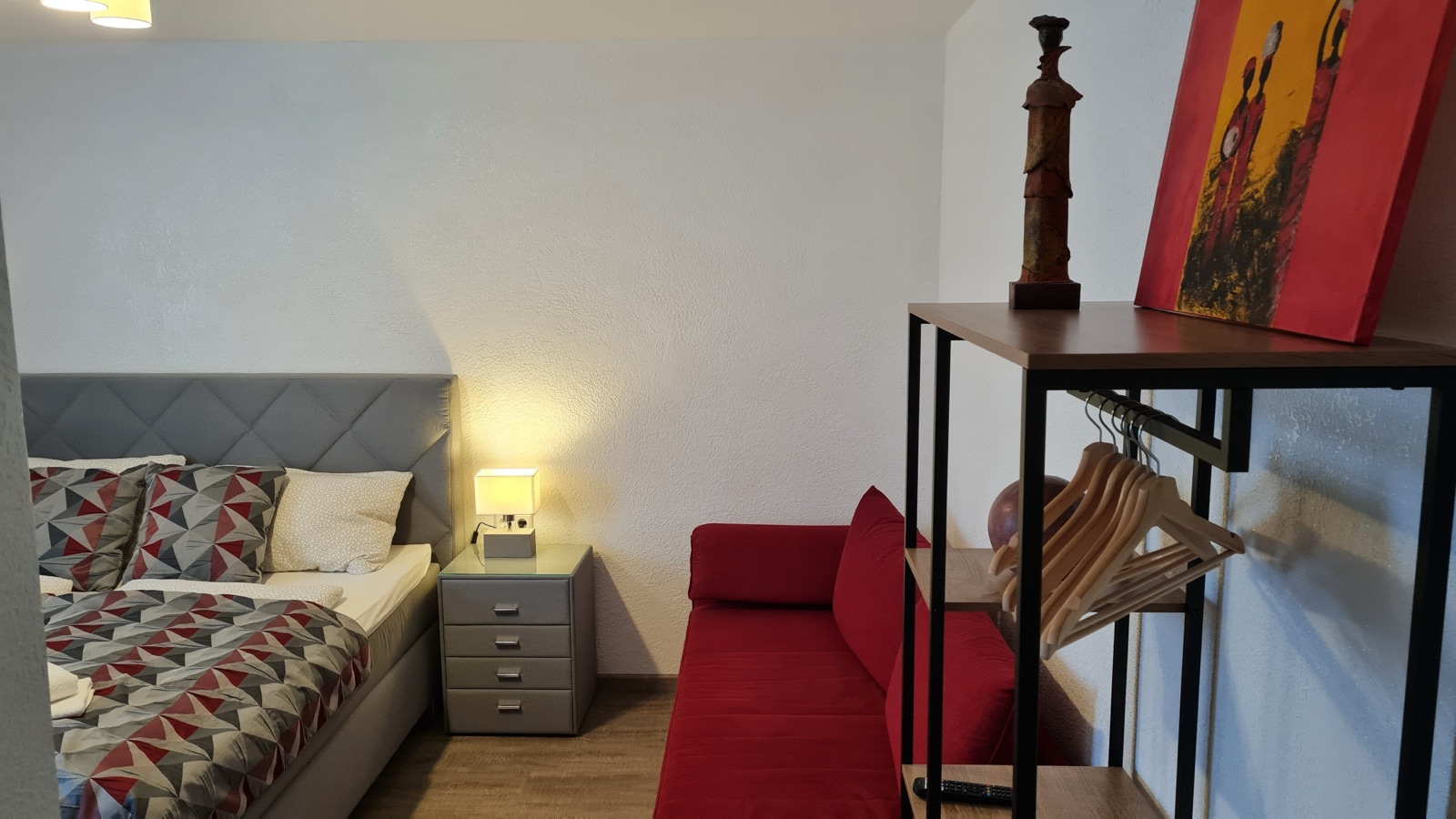 Sitzecke mit rotem Sessel neben dem Bett in Zimmer 7